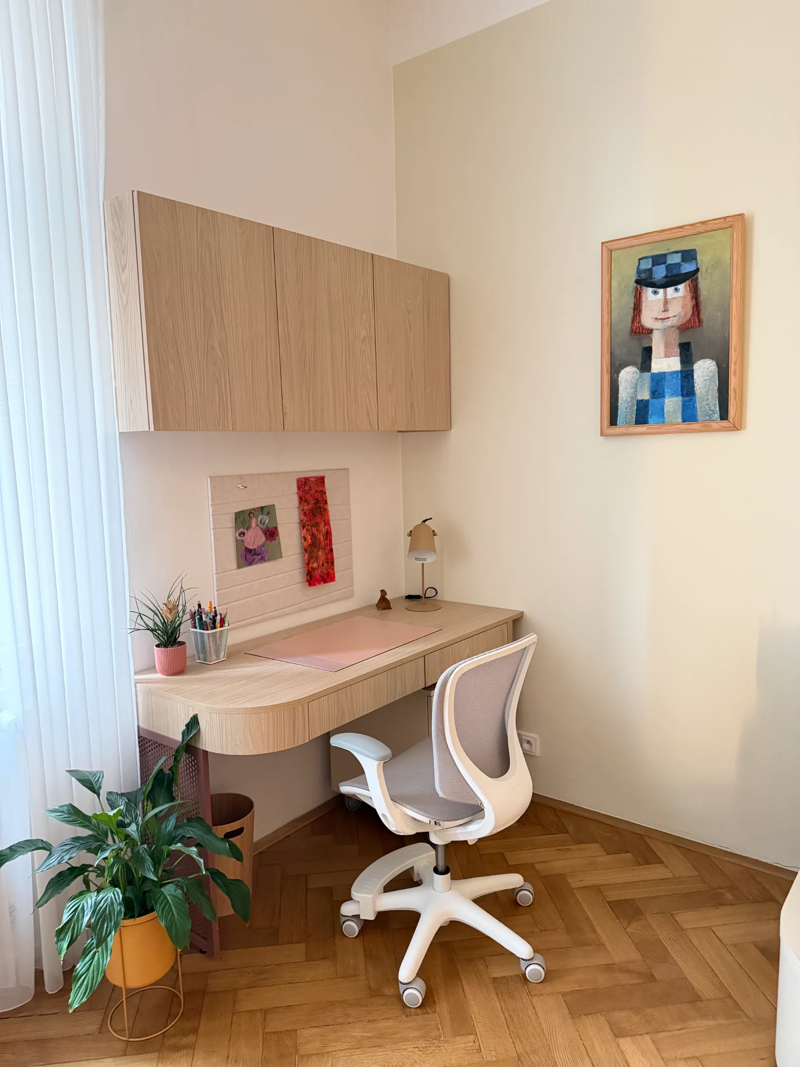 Světlý interiér pracovny s dřevěným stolem, skříňkami a židlí.